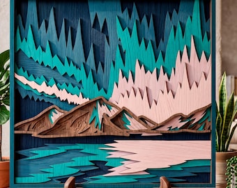 May include: A layered wooden art piece depicting a mountain landscape with a lake. The artwork features shades of teal, blue, brown, and pink. The piece is framed in a teal square frame and displayed on a wooden stand.
