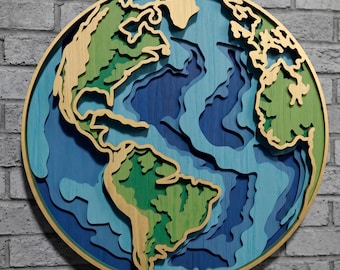 May include: A circular wall art piece featuring a layered, three-dimensional map of the world. The continents are rendered in shades of green and natural wood tones, while the oceans are depicted in multiple depths of blue, creating a topographic effect.