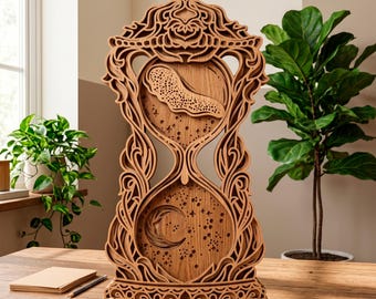 May include: A wooden hourglass sculpture with intricate layered designs. The sculpture features a crescent moon, stars, and a cloud-like shape within the hourglass. The wooden art piece is displayed on a wooden table.