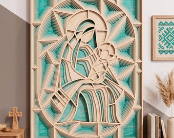 May include: A multi-layered wooden wall art piece featuring a stylized depiction of a figure holding a child. The design uses light-colored wood cutouts with recessed teal-colored panels, creating a deep, geometric, and dimensional effect.