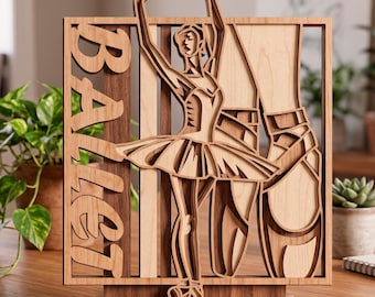 Puede incluir: Obra de arte de madera con temática de ballet. La palabra "BALLET" está recortada en el lado izquierdo. Se representa a una bailarina de ballet con los brazos levantados. La pieza está hecha de madera en capas en tonos marrón y beige, montada sobre una base de madera.