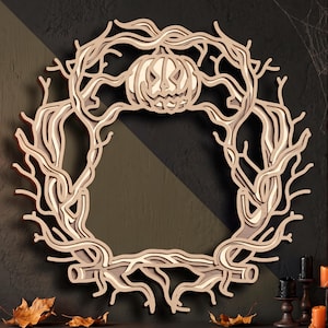 May include: A circular wall decoration crafted from layered light-coloured wood, featuring a detailed design of twisted, leafless tree branches forming a wreath. A carved jack-o'-lantern with a jagged, smiling face is positioned at the top centre.