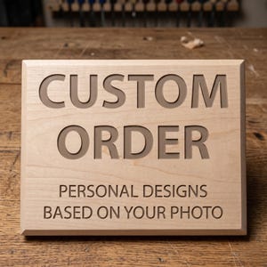 May include: A rectangular wooden sign with the words "CUSTOM ORDER" carved into the surface. Below, it reads "PERSONAL DESIGNS BASED ON YOUR PHOTO". The sign is made of light-colored wood.