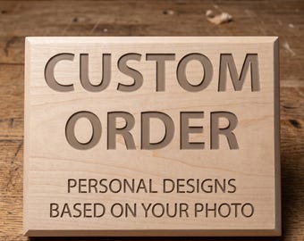 May include: A rectangular wooden sign with the words "CUSTOM ORDER" carved into the surface. Below, it reads "PERSONAL DESIGNS BASED ON YOUR PHOTO". The sign is made of light-colored wood.