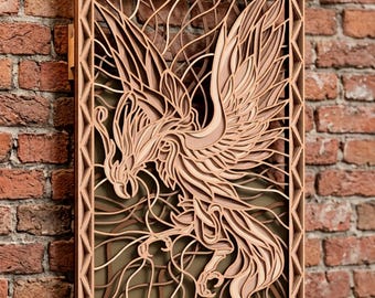 May include: A rectangular wall art piece featuring a multi-layered laser-cut wood design of a phoenix with outstretched wings. The artwork is enclosed in a geometric border frame with a dark olive green background behind the intricate bird figure.