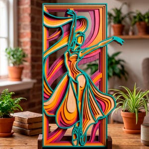 May include: A layered wooden art piece depicting a ballerina in motion. The artwork features a dancer in a flowing dress, with vibrant colors including teal, orange, pink, and yellow. The piece is framed and stands on a wooden base, showcasing a modern, artistic design.