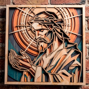 Op de afbeelding: Een meerlaags houten wandkunstwerk met een gestileerde afbeelding van een figuur met een halo, in profiel getoond met de handen samengevouwen in gebed. Het ontwerp gebruikt geometrische uitsparingen in tinten oranje, teal en naturel hout.