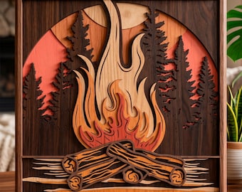 May include: A layered wooden art piece depicting a campfire scene. The artwork features a stylized flame in shades of orange and yellow, with logs at the base. The background includes trees and a sunset, all within a dark wood frame.