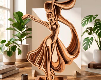 May include: A layered wooden sculpture of a ballerina in a flowing dress and scarf. The sculpture is made of various shades of wood, creating a 3D effect. The ballerina is posed mid-dance, with arms outstretched. The sculpture is displayed on a wooden stand.