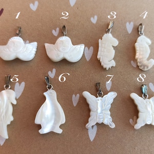 May include: Eight white mother of pearl pendants with silver bail. The pendants are shaped like an angel, a seahorse, a penguin, a butterfly, and a dolphin.