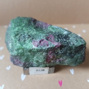 Peut inclure: Une pierre précieuse brute verte et rose avec une étiquette indiquant "RUB".