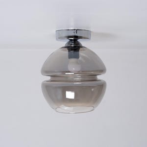 Op de afbeelding: Een chromen plafondlamp met een gelaagde, gerookte glazen kap.