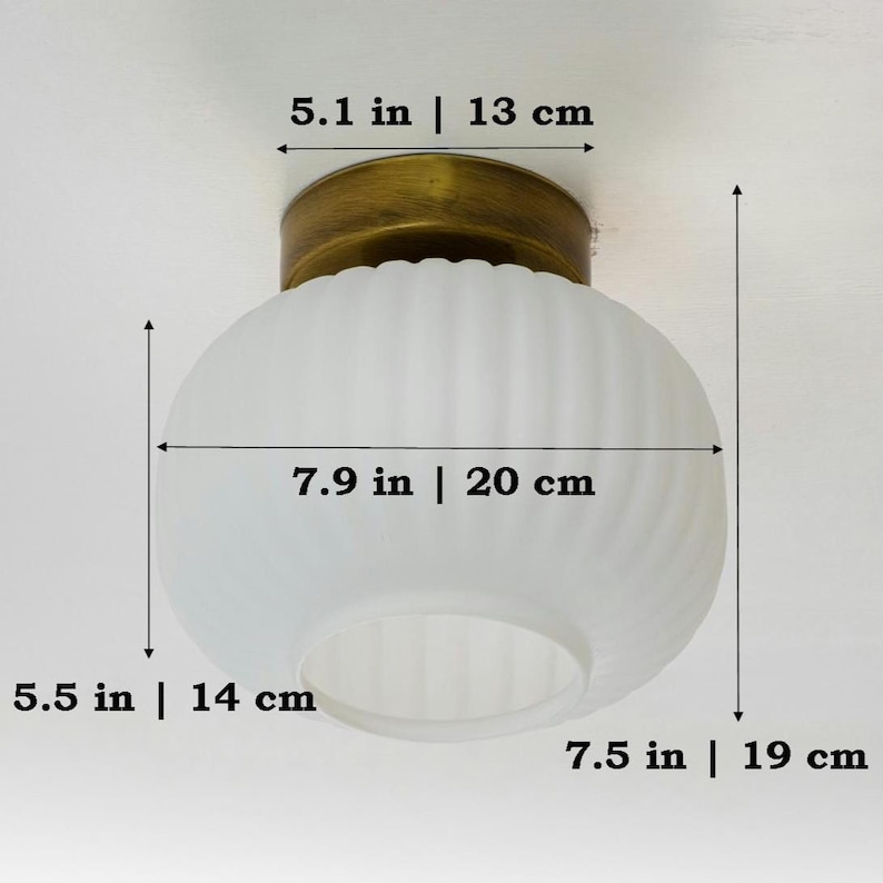Op de afbeelding: Een witte, gematteerde glazen plafondlamp met een messing basis. De lamp heeft een diameter van 20 cm en een hoogte van 14 cm.