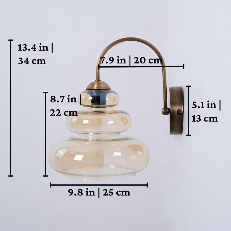 May include: A brass wall sconce with a layered amber glass shade. The sconce measures 13.4 inches tall, 9.8 inches wide, and 7.9 inches in diameter.