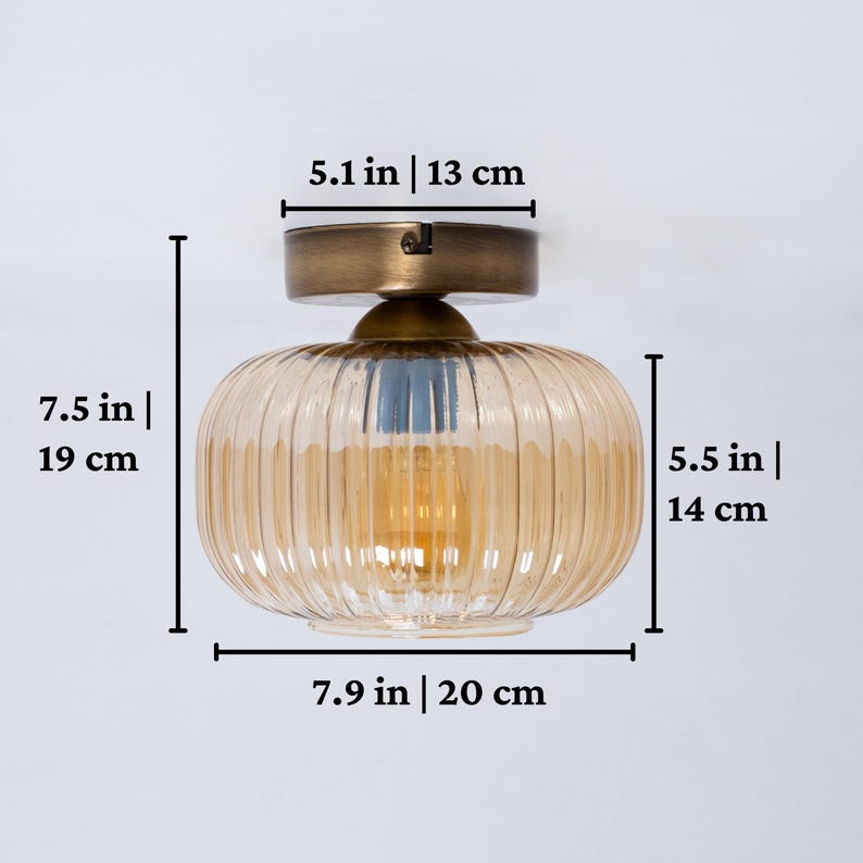 May include: A gold ceiling light fixture with a ribbed amber glass shade. The fixture measures 7.5 inches tall, 5.5 inches wide, and 7.9 inches in diameter.