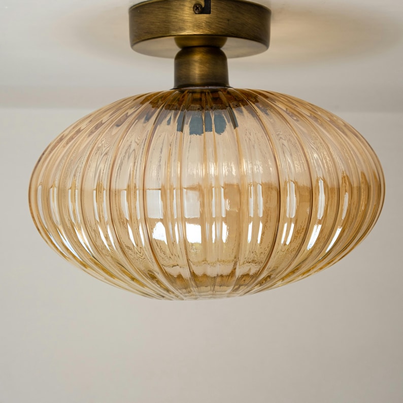 May include: A gold-toned ceiling light fixture with a ribbed amber glass shade.