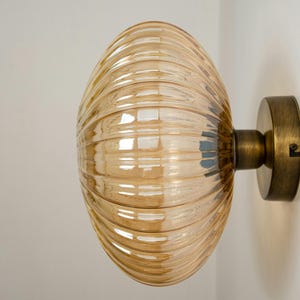 May include: A wall-mounted light fitting with a ribbed, amber glass shade and a brass base.