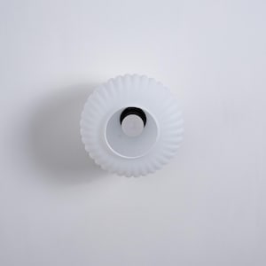 May include: White ceiling light fixture with a fluted glass shade.