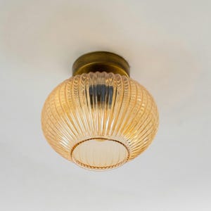 May include: A gold ceiling light fixture with a ribbed amber glass shade.
