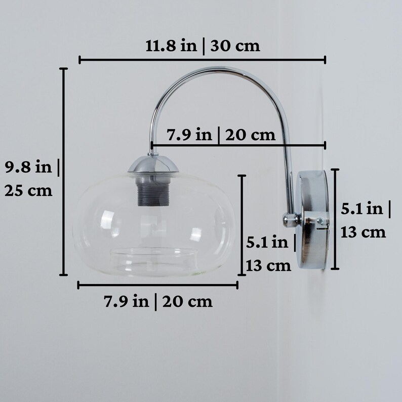 May include: Chrome wall sconce with a clear glass globe shade. The sconce measures 11.8 inches wide, 9.8 inches tall, and 5.1 inches deep.