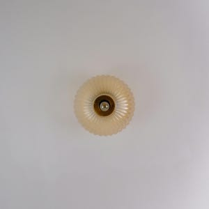 May include: A white ceiling light fixture with a round, ribbed glass shade.