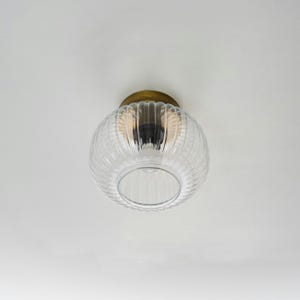 May include: A clear glass ceiling light fixture with a ribbed design and a brass finish.