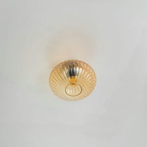 May include: A gold-toned ceiling light fixture with a ribbed glass shade.