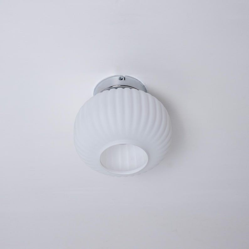 May include: A white ceiling light fixture with a ribbed glass shade and a chrome finish.