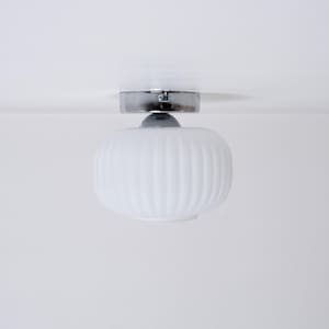 May include: A white ceiling light fixture with a ribbed glass shade and a chrome finish.
