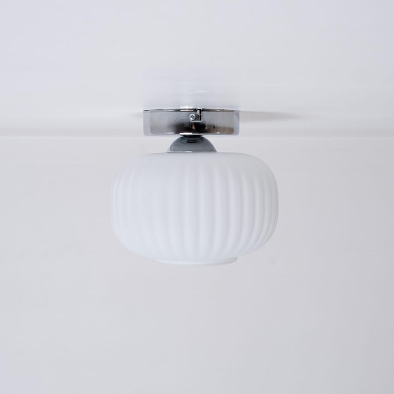 May include: A white ceiling light fixture with a ribbed glass shade and a chrome finish.
