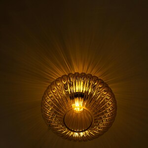 May include: A gold-toned, ribbed glass ceiling light fixture with a warm, glowing light emanating from the center.