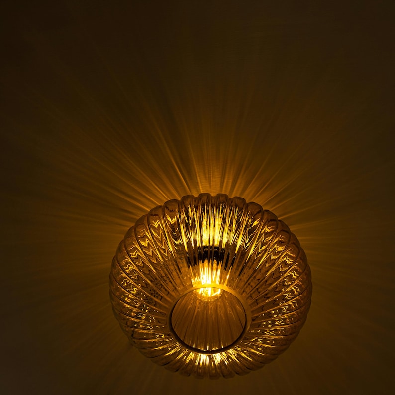 May include: A gold-toned, ribbed glass ceiling light fixture with a warm, glowing light emanating from the center.