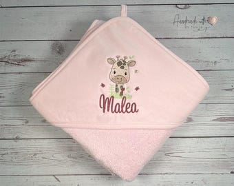 May include: Pink hooded towel with a cute embroidered giraffe and the name Malea. The towel is made of soft, absorbent material.