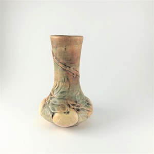May include: A small, brown and green ceramic vase with a floral design and a bulbous base. The vase is decorated with a vine and fruit motif.