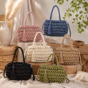 May include: A collection of six macrame handbags in pink, blue, cream, beige, black, and olive green. Each bag features a woven lattice pattern, two braided top handles, a detachable shoulder strap, and a matching decorative tassel charm.