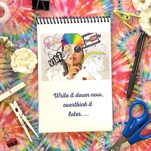 Peut inclure: Un carnet à spirales blanc avec un collage coloré sur la couverture. Le collage comprend des images d'une femme, d'un arc-en-ciel, d'un appareil photo et les mots "You Tube Yo" et "VIDEO". Le carnet porte l'inscription "Write it down now, overthink it later..." sur la couverture.