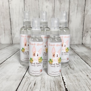 May include: Six clear glass bottles with spray tops, each containing a clear liquid. The bottles have labels with a cartoon dog and the text "Peach-Hound Island Nectar Tursuit Spray 2 fl oz / 59 ml www.peach-hound.com"
