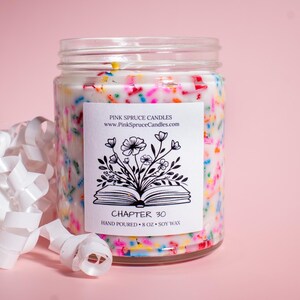 May include: A white candle jar with a black and white label that says "Chapter 30" and "Pink Spruce Candles". The candle is filled with white wax and colorful sprinkles.