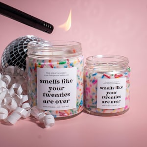 May include: Two candles with a white background and colorful sprinkles. The candles have labels that say "smells like your twenties are over".
