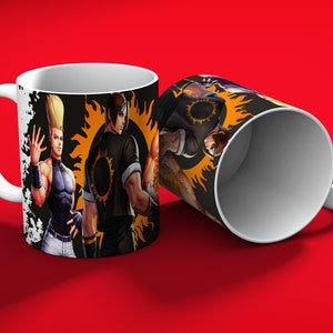 May include: White ceramic mug featuring illustrations of characters from a fighting game. The design includes a character with spiky blonde hair and another in a black outfit with a sun emblem. The mug is set against a red background.