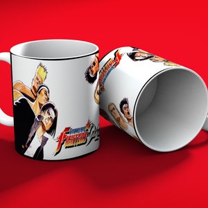 May include: Two white ceramic mugs with a black rim and handle, featuring a colorful graphic of characters from the video game "The King of Fighters". The mugs are set against a red background.