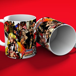 May include: White ceramic mug featuring a colorful collage of characters from the video game "The King of Fighters 2002". The mug has a white handle and a vibrant design on the exterior, set against a red background.