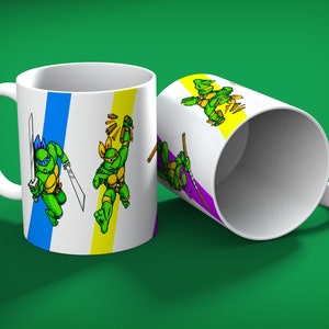 May include: White ceramic mug featuring the Teenage Mutant Ninja Turtles. The mug has a handle and is decorated with images of the turtles in action poses, with blue, yellow, and purple stripes. The background is a solid green.