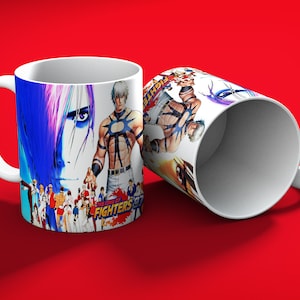 May include: White ceramic mug featuring illustrations of characters from "The King of Fighters '97" video game. The mug displays various characters in action poses, with the game's title prominently displayed. The mug has a white handle and a red background.