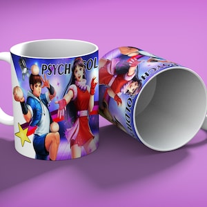 May include: White ceramic mug featuring a colorful illustration of two anime characters with the text "PSYCHO SOLDIER". One character is in a blue jacket, and the other is in a red dress. The mug is on a purple background.