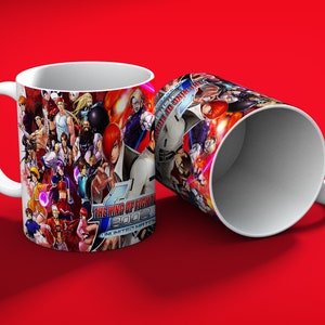 May include: Two white ceramic mugs with a vibrant design featuring characters from "The King of Fighters 2002: Unlimited Match" video game. The mugs have a red background.