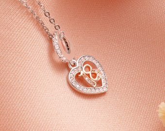 May include: A silver necklace with a heart-shaped pendant. The pendant features a gold-colored number "18" inside a heart outline, surrounded by small, clear crystals. The necklace chain is delicate and silver.
