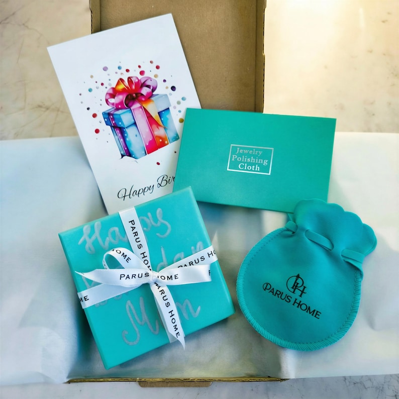 Puede incluir: Un juego de regalo con una caja turquesa atada con una cinta blanca, una bolsa a juego y una tarjeta que dice "Happy Birthday". La caja y la bolsa tienen la marca "PARUS HOME" impresa. Tambi&eacute;n se incluye un pa&ntilde;o para pulir joyas.