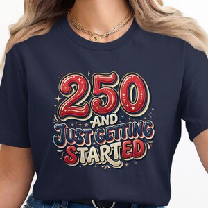 May include: Navy blue t-shirt with the number "250" in red and white, and the phrase "AND JUST GETTING STARTED" in a decorative font. The design has a vintage, celebratory style.