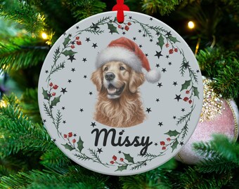 Könnte beinhalten: Runder Weihnachtsschmuck mit einem Golden Retriever mit Weihnachtsmütze. Der Schmuck hat einen hellgrauen Hintergrund mit einem Rand aus Stechpalmen und Sternen. Der Name des Hundes, "Missy", ist kursiv geschrieben.